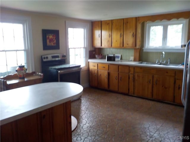 kitchen with brown cabinets, light countertops, a sink, and backsplash