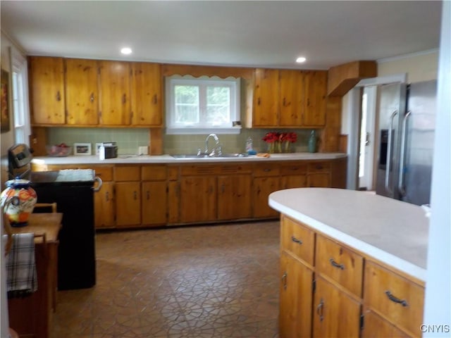 kitchen with light countertops, stainless steel refrigerator with ice dispenser, a sink, and brown cabinets