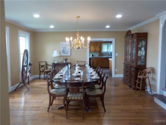 dining room with light wood-type flooring, plenty of natural light, baseboards, and crown molding