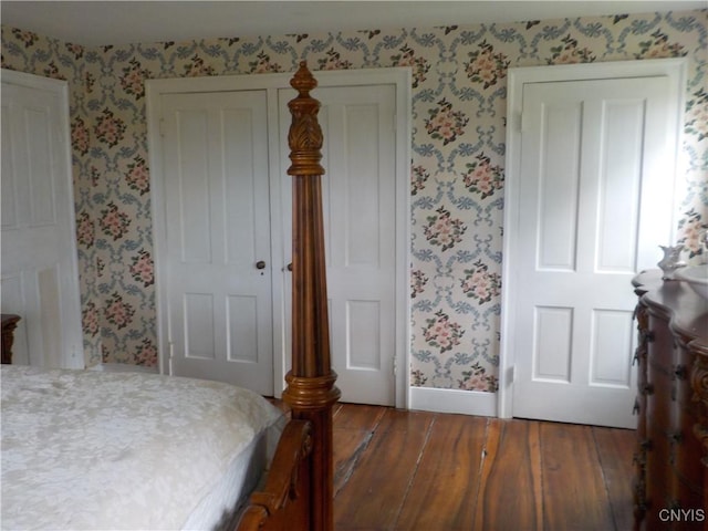 bedroom with baseboards, wood finished floors, and wallpapered walls