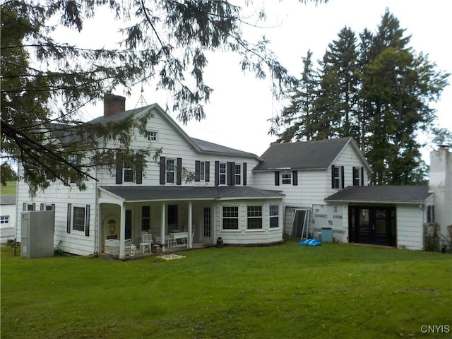 rear view of house with a yard, a porch, and a chimney