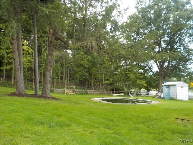 view of yard featuring a shed, fence, and an outbuilding