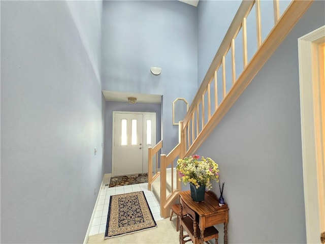 doorway with baseboards, stairway, a high ceiling, and tile patterned floors