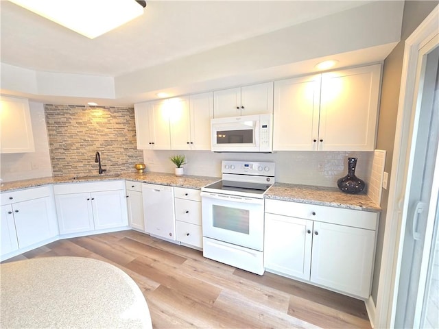 kitchen featuring white appliances, a sink, light wood-style flooring, and white cabinetry