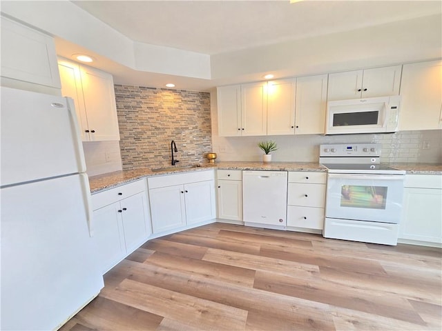 kitchen with white appliances, white cabinets, a sink, and light wood finished floors