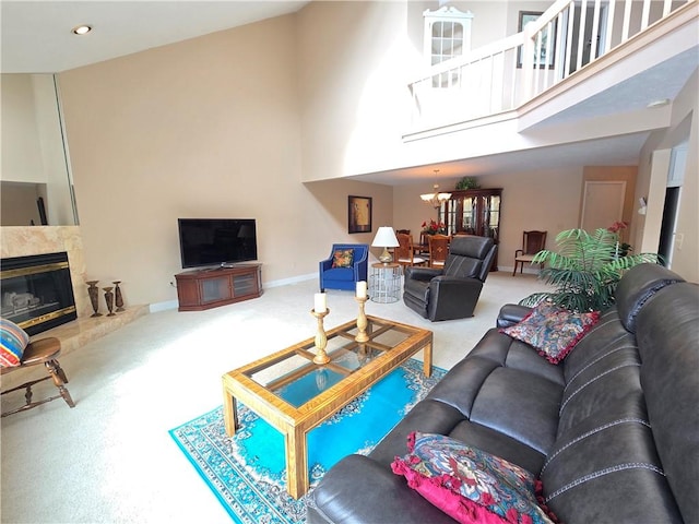 carpeted living room with a tile fireplace, a towering ceiling, baseboards, and an inviting chandelier