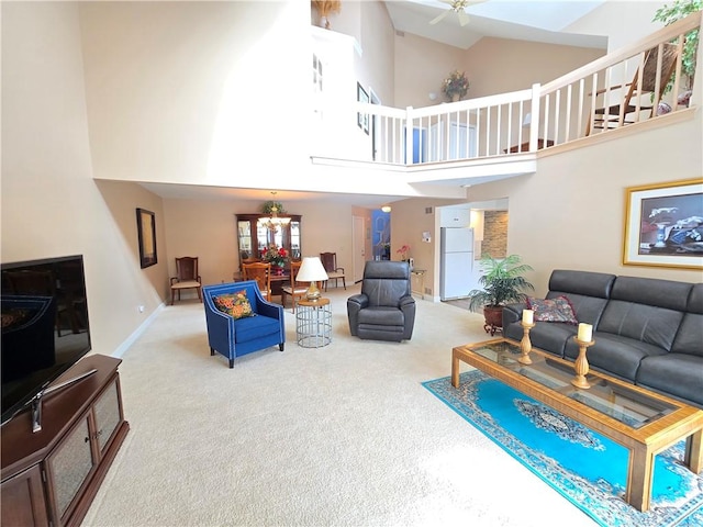 living area with a ceiling fan, carpet flooring, a towering ceiling, and baseboards