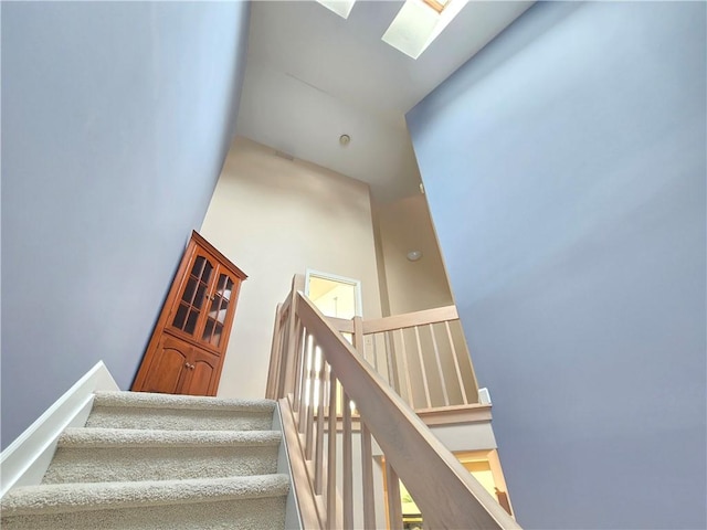 staircase with a skylight and a high ceiling