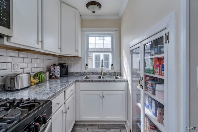 kitchen with stainless steel appliances, backsplash, a sink, and white cabinetry