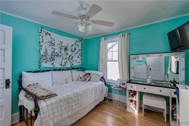 bedroom featuring ceiling fan, baseboards, hardwood / wood-style flooring, and crown molding