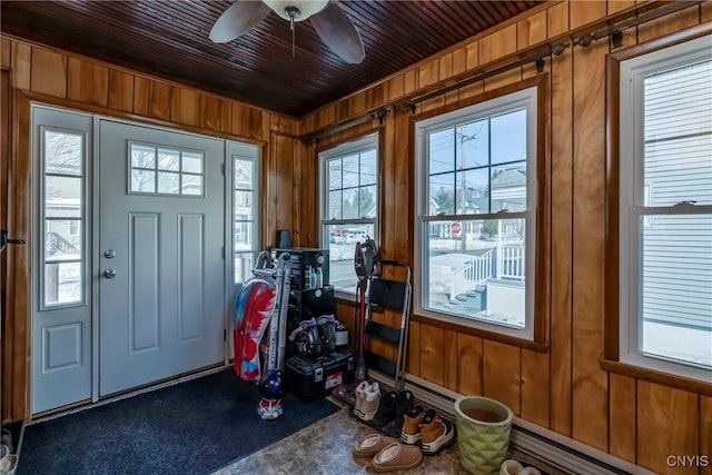 interior space with a baseboard heating unit, ceiling fan, wood ceiling, and wooden walls