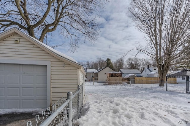 yard covered in snow with a garage, fence, and an outdoor structure