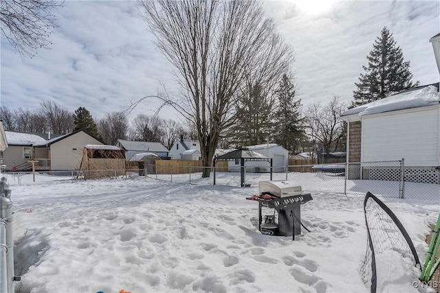 snowy yard featuring an outdoor structure, a fenced backyard, and a residential view