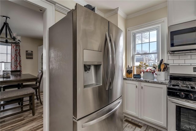 kitchen with stainless steel appliances, plenty of natural light, visible vents, and crown molding