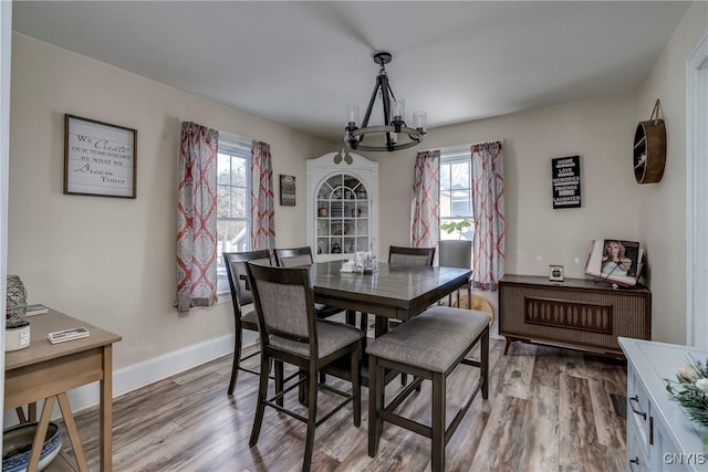 dining area featuring a chandelier, light wood-style flooring, and baseboards