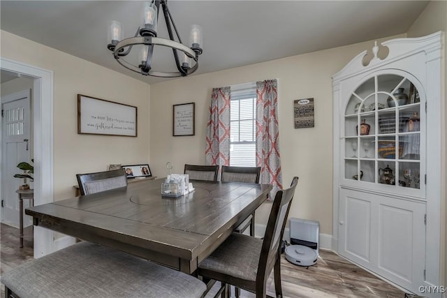 dining area with baseboards, wood finished floors, and an inviting chandelier