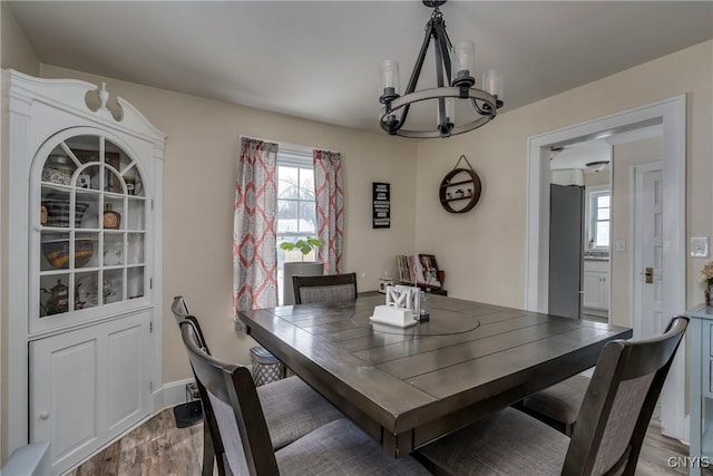 dining area with light wood finished floors, a wealth of natural light, and an inviting chandelier