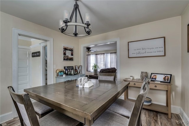 dining room featuring baseboards, wood finished floors, and ceiling fan with notable chandelier