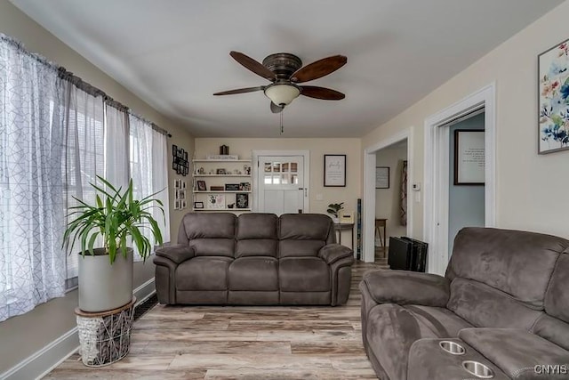 living room featuring light wood-style flooring, baseboards, and ceiling fan