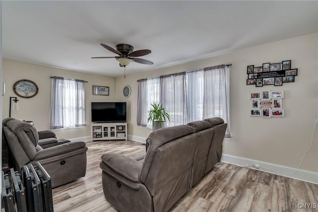 living area featuring a ceiling fan, light wood-type flooring, and baseboards