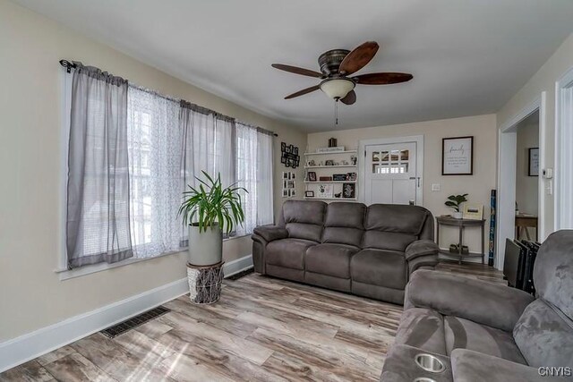 living room featuring baseboards, visible vents, ceiling fan, and wood finished floors