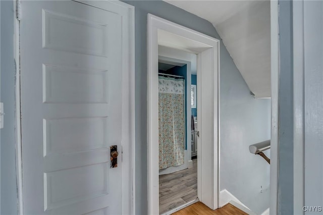 hallway with lofted ceiling and light wood finished floors