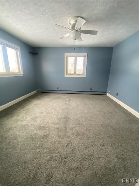 carpeted spare room with ceiling fan, baseboards, baseboard heating, and a textured ceiling