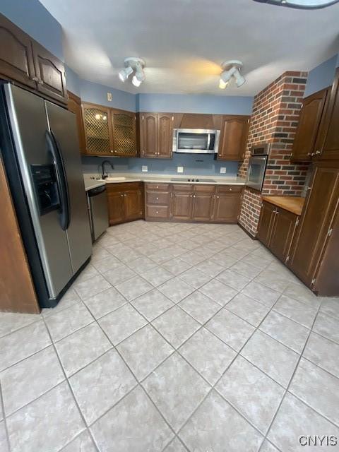 kitchen featuring a sink, stainless steel appliances, light tile patterned floors, and light countertops