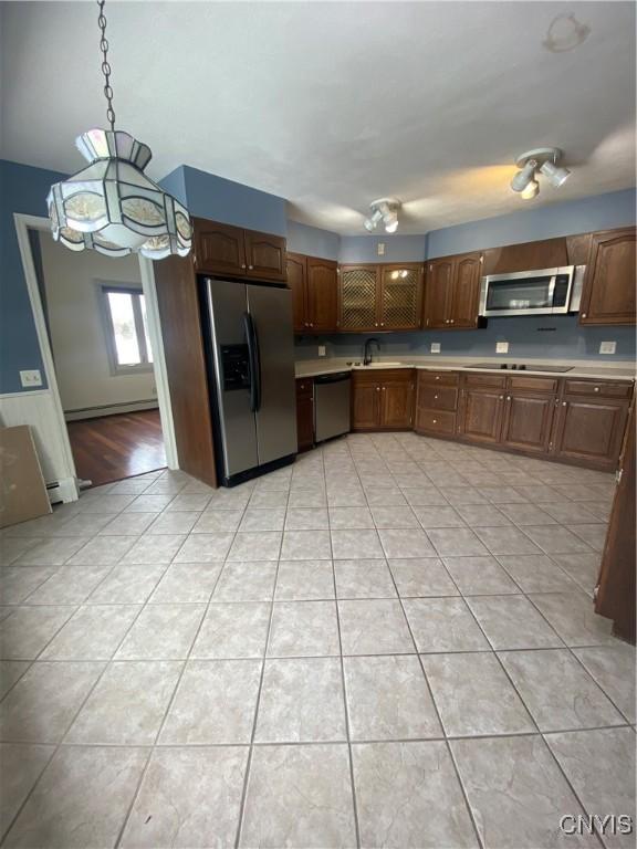 kitchen featuring light tile patterned floors, a baseboard heating unit, stainless steel appliances, a sink, and light countertops