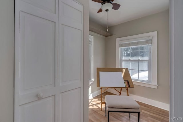 sitting room with light wood finished floors, a ceiling fan, and baseboards