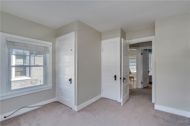 unfurnished bedroom featuring baseboards and light colored carpet