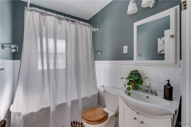 bathroom featuring toilet, a wainscoted wall, and vanity