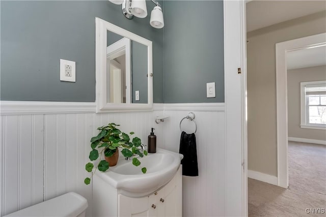 half bath featuring a wainscoted wall and vanity