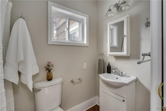 bathroom with toilet, vanity, and baseboards