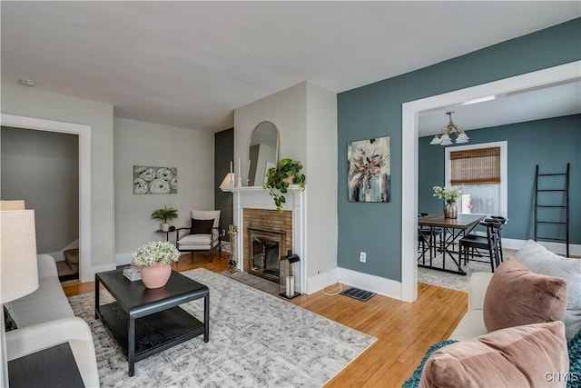 living room with light wood-style floors, a fireplace, and baseboards