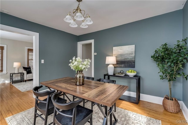 dining area with an inviting chandelier, light wood-style flooring, and baseboards