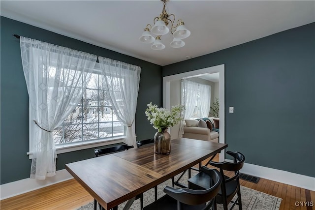 dining room featuring light wood-style floors, a notable chandelier, and baseboards