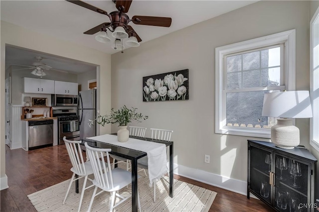 dining space with ceiling fan, dark wood finished floors, and baseboards