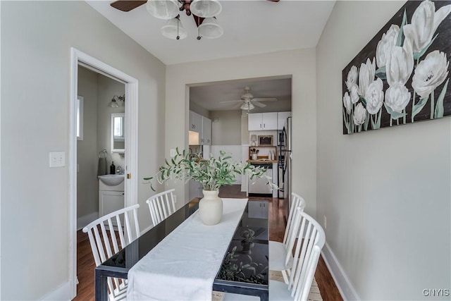 dining room with a ceiling fan, baseboards, and wood finished floors