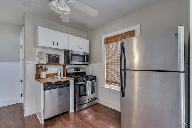 kitchen featuring stainless steel appliances, white cabinets, wainscoting, and dark wood-type flooring