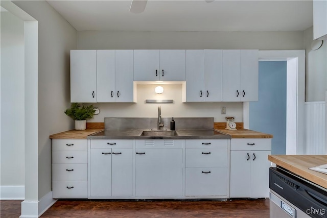 kitchen featuring baseboards, white cabinets, stainless steel countertops, dark wood-style flooring, and a sink