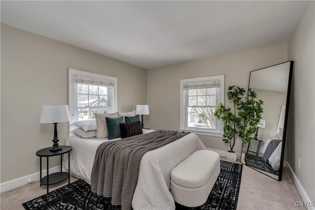 bedroom with multiple windows, light carpet, and baseboards