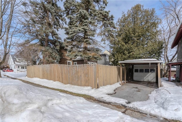 yard layered in snow featuring a garage and fence