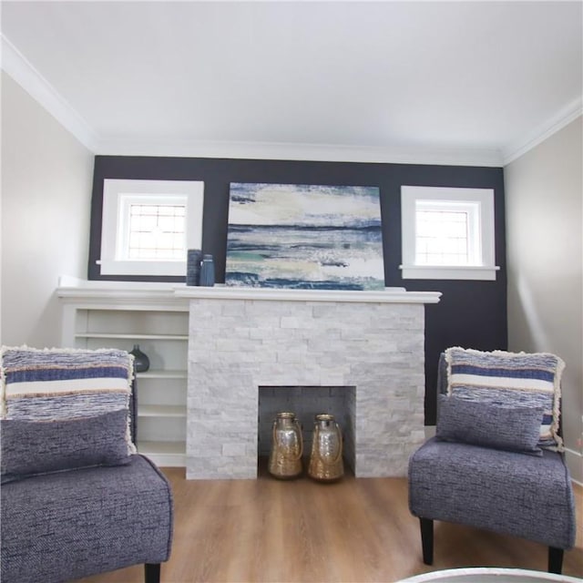 sitting room featuring ornamental molding, a stone fireplace, and wood finished floors