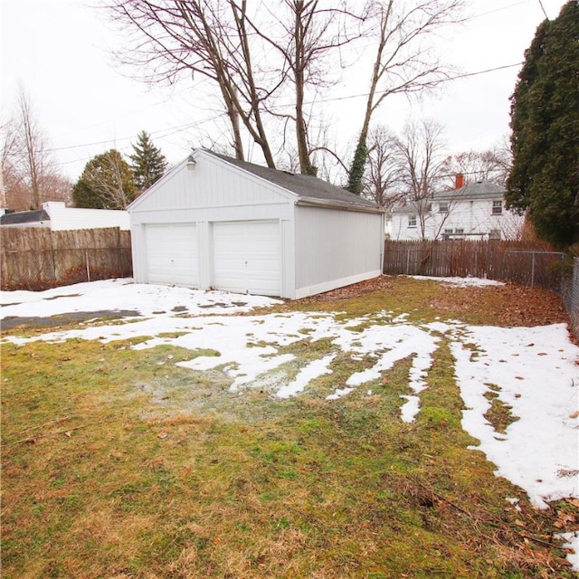 snow covered garage featuring a garage and fence