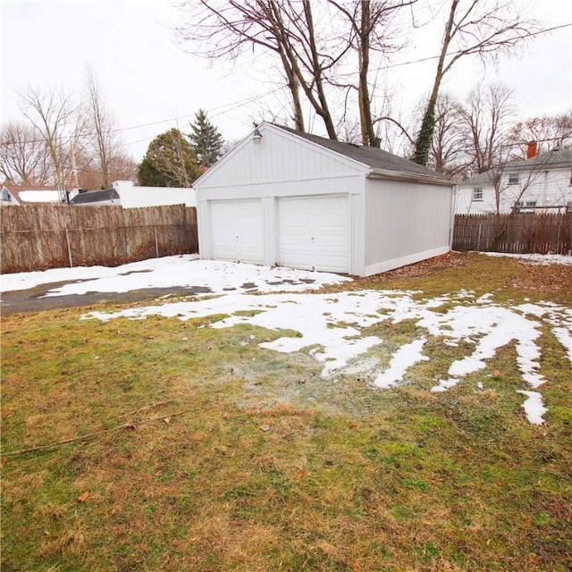 snow covered garage with a garage and fence