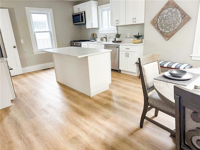 kitchen with appliances with stainless steel finishes, light wood-type flooring, a wealth of natural light, and light countertops