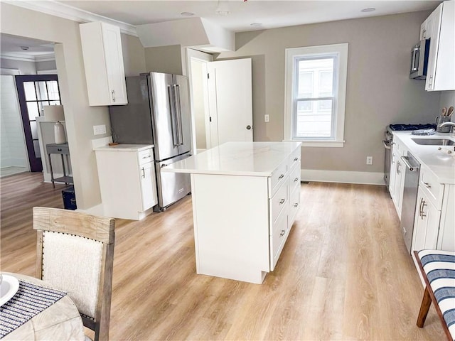 kitchen with light wood-style flooring, a kitchen island, stainless steel appliances, and light countertops