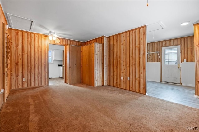 unfurnished room featuring plenty of natural light, attic access, and wooden walls