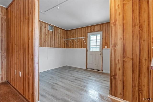 spare room with wood walls, attic access, visible vents, and wood finished floors